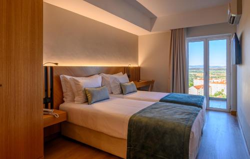 科维良Santa Eufémia Covilhã Hotel的酒店客房设有一张床和一个大窗户