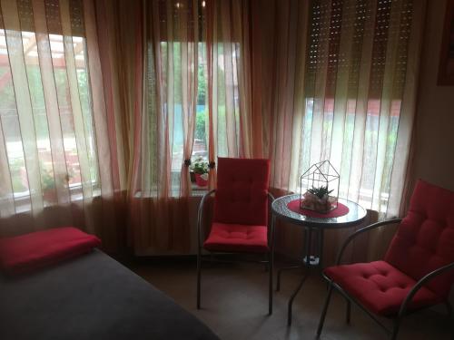巴拉顿菲兹弗Betty Apartman的一间卧室设有两张红色椅子和一张桌子,窗户