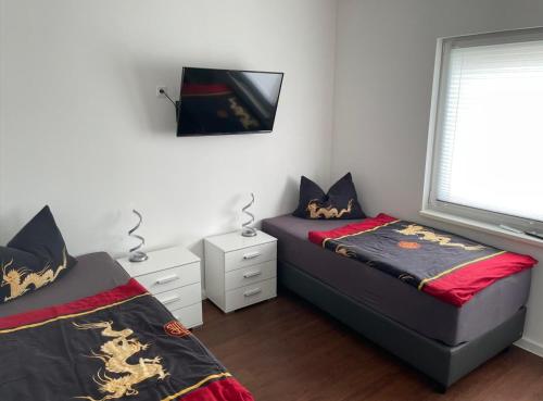 新勃兰登堡Tollenseheim的一间卧室设有两张床,墙上配有电视。