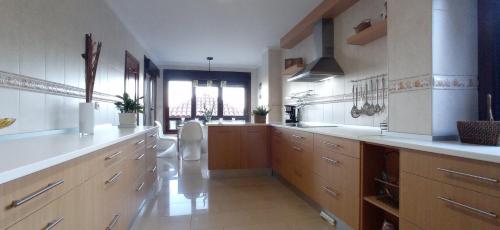 莫阿尼亚Itxi y Jamin - Chalet con vistas a la Ria de Vigo的一间设有白色柜台和木制橱柜的大厨房