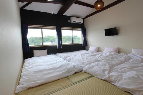 志摩市Yadokari Shima的配有窗户的客房内设有两张大型白色床。