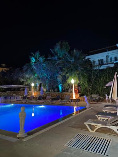 厄吕代尼兹Nefis Hotel Ölüdeniz的游泳池,晚上配有椅子和棕榈树