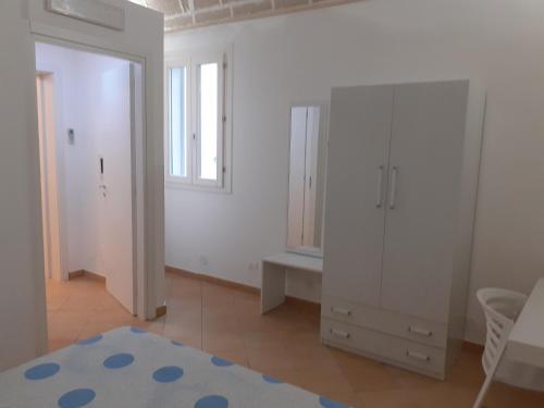 马里迪莫La Dimora Del Vento的卧室配有白色橱柜、窗户和镜子