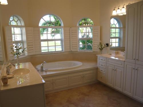 珊瑚角Villa Cape Florida的带浴缸和两个盥洗盆的浴室以及窗户。