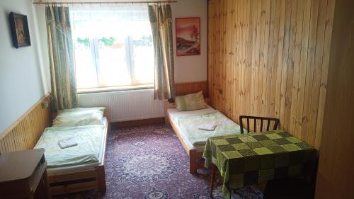 亚沃尔尼克Hostinec Na Návsi的客房设有两张床、一张桌子和一扇窗户。