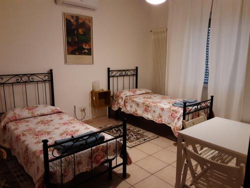 帕多瓦Locazione Menini - Camere zona stazione的一间卧室配有两张床、一张桌子和一张桌子
