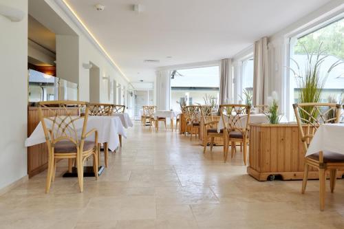塞巴特阿尔贝克Hotel Residenz WALDOASE的餐厅设有白色的桌椅和窗户。