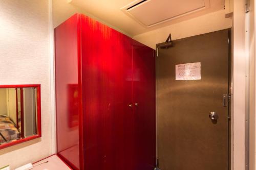 贝冢市日出酒店的红色淋浴的浴室,有红色的门