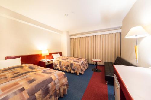 贝冢市日出酒店的酒店客房,设有两张床和一张沙发