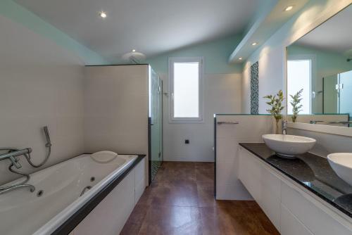 休达德亚Villa Santandria Grupo Seranova Luxury Hotel的浴室配有两个盥洗盆、浴缸和浴缸。