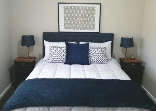 尤罗亚Kennedy House Euroa A delightful place to stay的一间卧室配有一张带蓝色和白色枕头的床