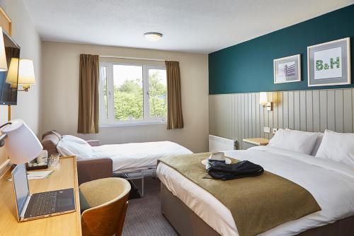 奥尔德姆Boat & Horses Inn的酒店客房配有两张床和一张带笔记本电脑的书桌