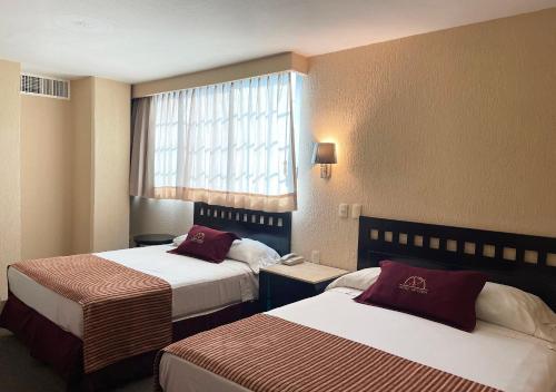 伊达尔戈州波萨里卡Hotel Victoria Poza Rica by Brahma的酒店客房设有两张床和窗户。