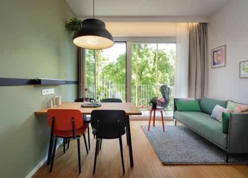 维也纳Zoku Vienna的客厅配有桌子和绿色沙发