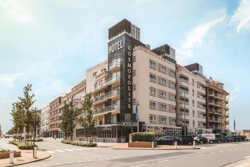 尼乌波特Cosmopolite Hotel Nieuwpoort-Bad的一座白色的大建筑,旁边有一个标志