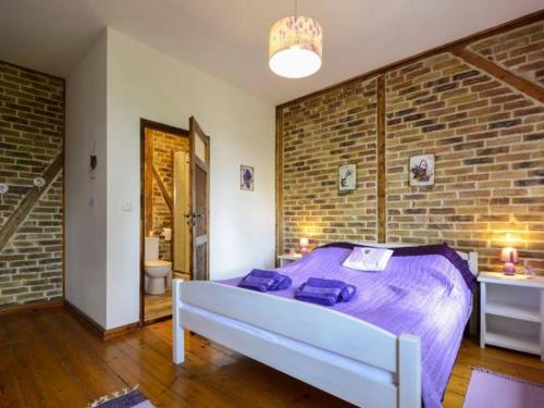 斯克拉斯卡波伦巴Willa Sielsko Anielsko的一间卧室配有一张带紫色床单和砖墙的床。