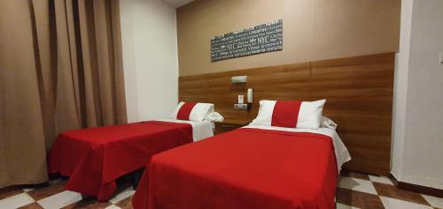 加的斯Hostal San Francisco的配有红色和白色床单的客房内的两张床
