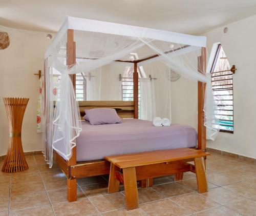 巴卡拉尔艾克图堪别墅旅馆的一间卧室设有一张天蓬床和一张木凳