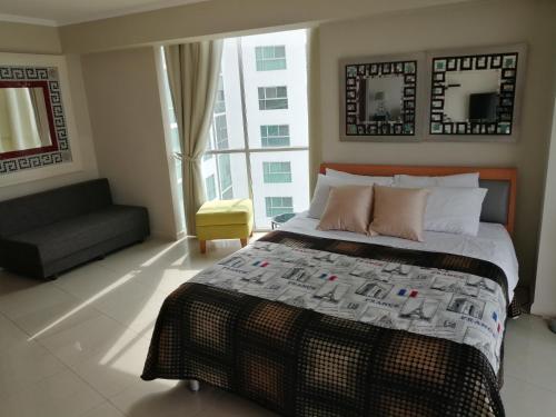 瓜亚基尔River View Suites Guayaquil的一间卧室配有一张床、一张沙发和一个窗口