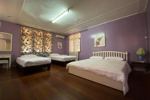 古晋OYO Home 90287 Rb Homestay & Farms的一间卧室设有两张床和紫色墙壁