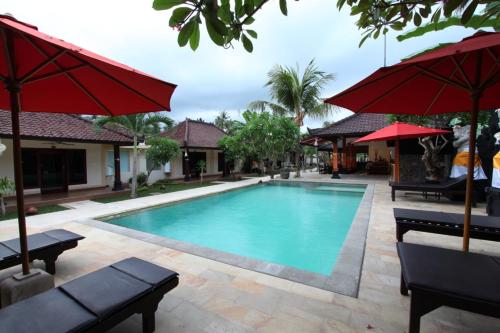 罗威那梅拉姆酒店的度假村的游泳池配有遮阳伞和长椅
