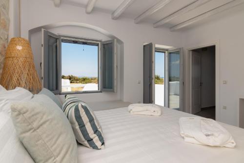 纳克索乔拉Isalos Villas Naxos的白色卧室设有一张大白色的窗户