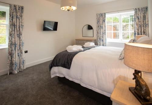 桑希尔Laundry Cottage: Drumlanrig Castle的卧室设有一张白色大床和两个窗户。