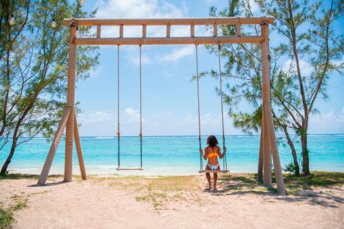 贝尔马尔C Mauritius - All Inclusive的坐在海滩秋千上的一个小女孩