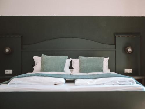 巴特维塞LEDA AM ECK的一张带黑色床头板和绿色枕头的床
