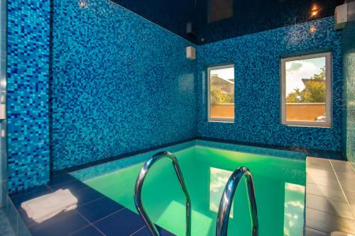 第聂伯罗Отель Корона的蓝色瓷砖浴室设有浴缸和2扇窗户
