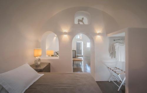 FoinikiáAQUA SERENITY LUXURY SUITES SANTORINI的一间卧室配有一张床,另一间卧室配有椅子