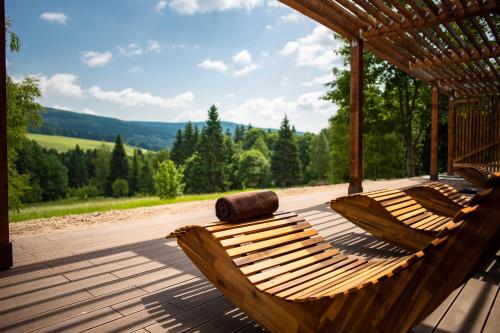 德尔内夫奥里克Amenity Hotel & Resort Orlické hory的甲板上设有两张木制吊床,享有山景