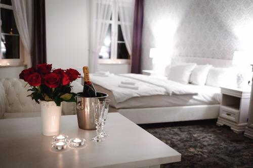 新苏尔Hotel Nadodrzański Dwór - Nowa Sól的一间卧室配有一张床和一张桌子及一瓶葡萄酒