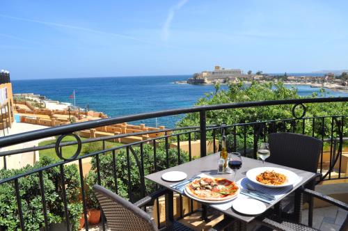 圣朱利安斯马耳他科林西亚海滩海滨度假酒店的阳台上摆放着两盘食物的桌子