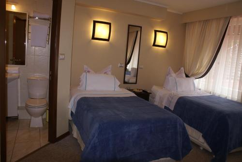 La MáquinaVilla Baviera, Hotel Baviera Chile的酒店客房设有两张床和卫生间。