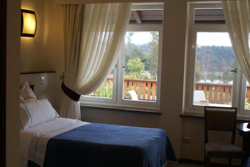 La MáquinaVilla Baviera, Hotel Baviera Chile的一间卧室配有一张床,两个窗户和阳台