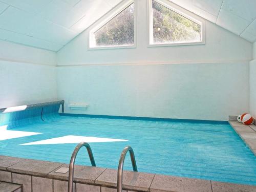 维斯特索马肯12 person holiday home in Aakirkeby的一个带蓝色墙壁和窗户的大型游泳池