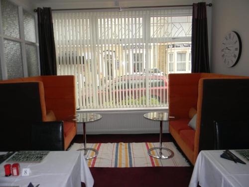 布莱克浦Devon Guest House的客房设有两把橙色椅子和大窗户