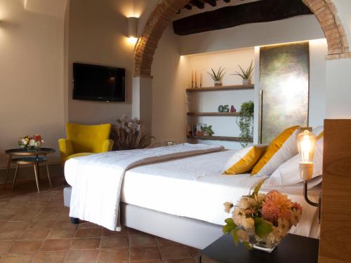 蒙特普齐亚诺科尔特瑟格拉特旅馆的卧室配有一张白色大床和黄色椅子