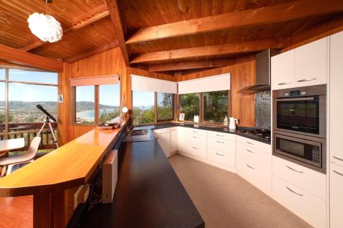玛莎山Kinoie Mornington - OCEANVIEW的厨房配有白色橱柜、木质天花板和窗户。
