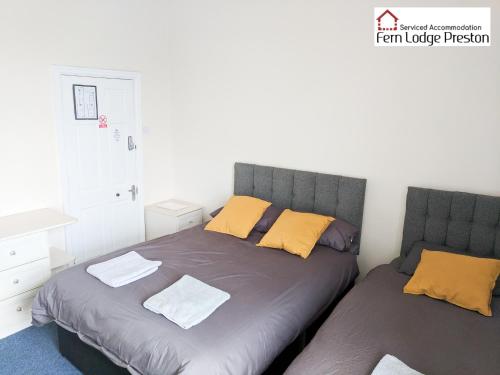 普雷斯顿4 Bedroom House at Fern Lodge Preston Serviced Accommodation - Free WiFi & Parking的一间卧室配有两张带黄色枕头的床