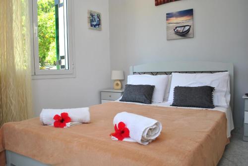 朗戈斯Loggos Seaview Cottage with Pool by Konnect的一间卧室配有带毛巾和红色鲜花的床。
