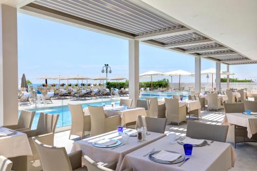 利多迪耶索罗卡瓦列利皇宫酒店的一间带白色桌椅的餐厅和一个游泳池