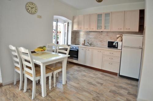 布德瓦Bell Tower Apartment的厨房配有白色的桌椅和白色的冰箱。