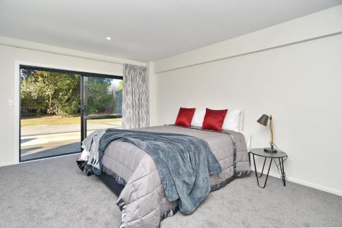 基督城Lavandula 4 - Christchurch Holiday Homes的一间卧室配有一张带红色枕头的大床