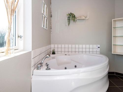 法贾德嘉德8 person holiday home in Ulfborg的带窗户的浴室内的白色浴缸
