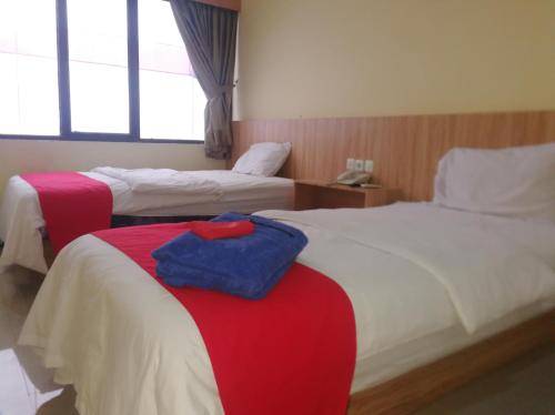 占碑市Hotel Mayang Sari 2的酒店客房,设有两张红色和白色的床