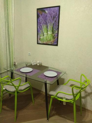 ShostkaХорошая однокомнатная квартира в центре города的一张玻璃桌,配有两把椅子和墙上的一幅画