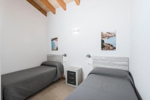 卡兰博希Villa Calan Bosch Es Bruc的白色墙壁客房的两张床