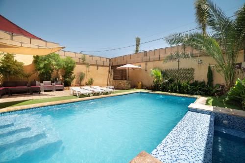 索瓦马Orient Villa-Dead Sea的庭院内的游泳池配有椅子和遮阳伞